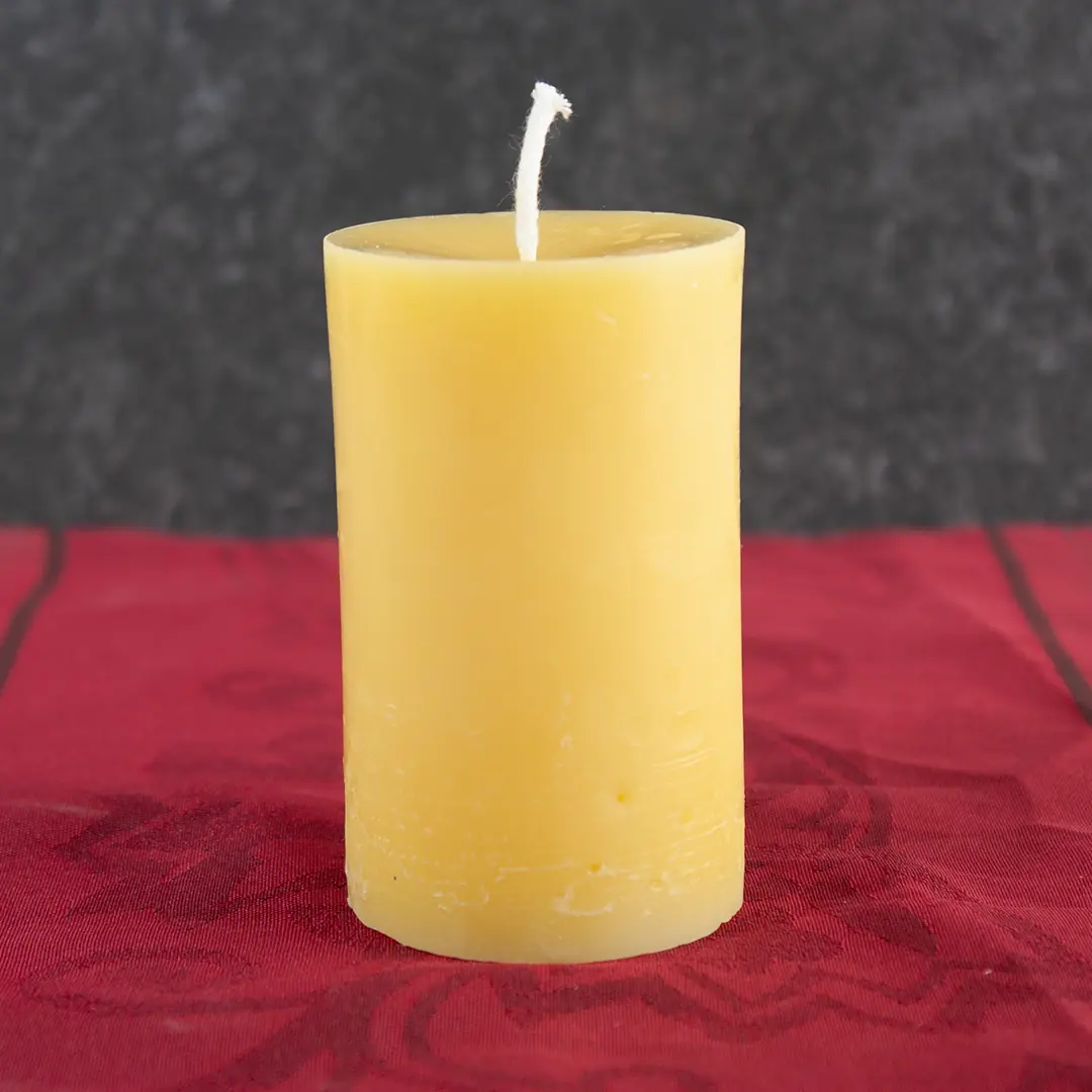 Goldgelbe Bienenwachs-Stumpfkerze 4cm Durchmesser und 6cm Höhe auf dunklem Untergrund