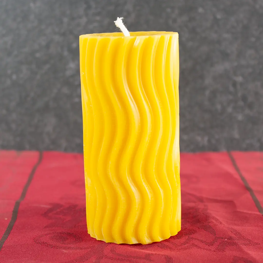 Goldgelbe Bienenwachs-Stumpfkerze mit geschwungenem Sternenmuster in Wellenform, 6cm Durchmesser und 11,5cm Höhe