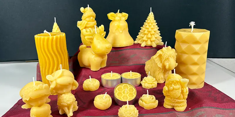 Brennende Bienenwachskerzen in verschiedenen Formen auf Holztisch mit Tannenzweigen und Weihnachtsdekoration