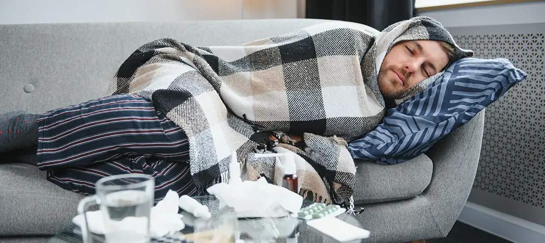 Person ruht sich im Bett aus mit Tee und Honig bei Erkältung